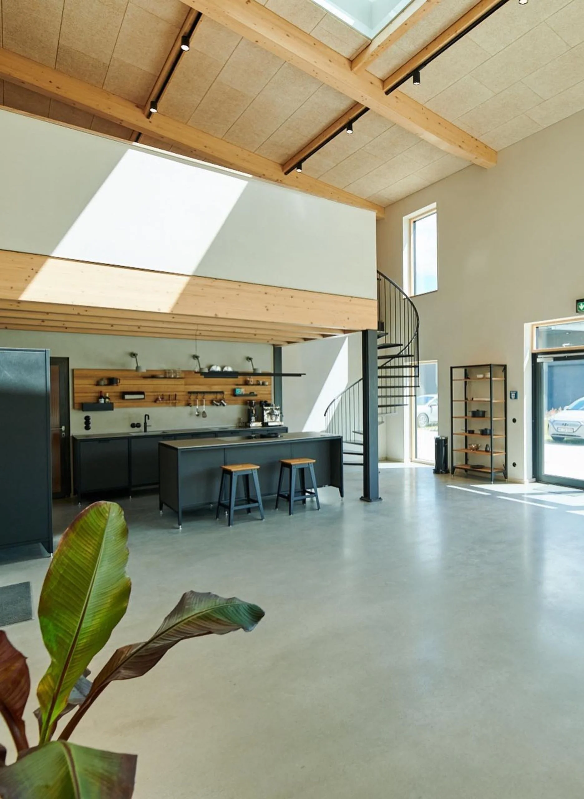 Intérieur lumineux d’une halle X-Wood® avec plafond en bois apparent et mezzanine
