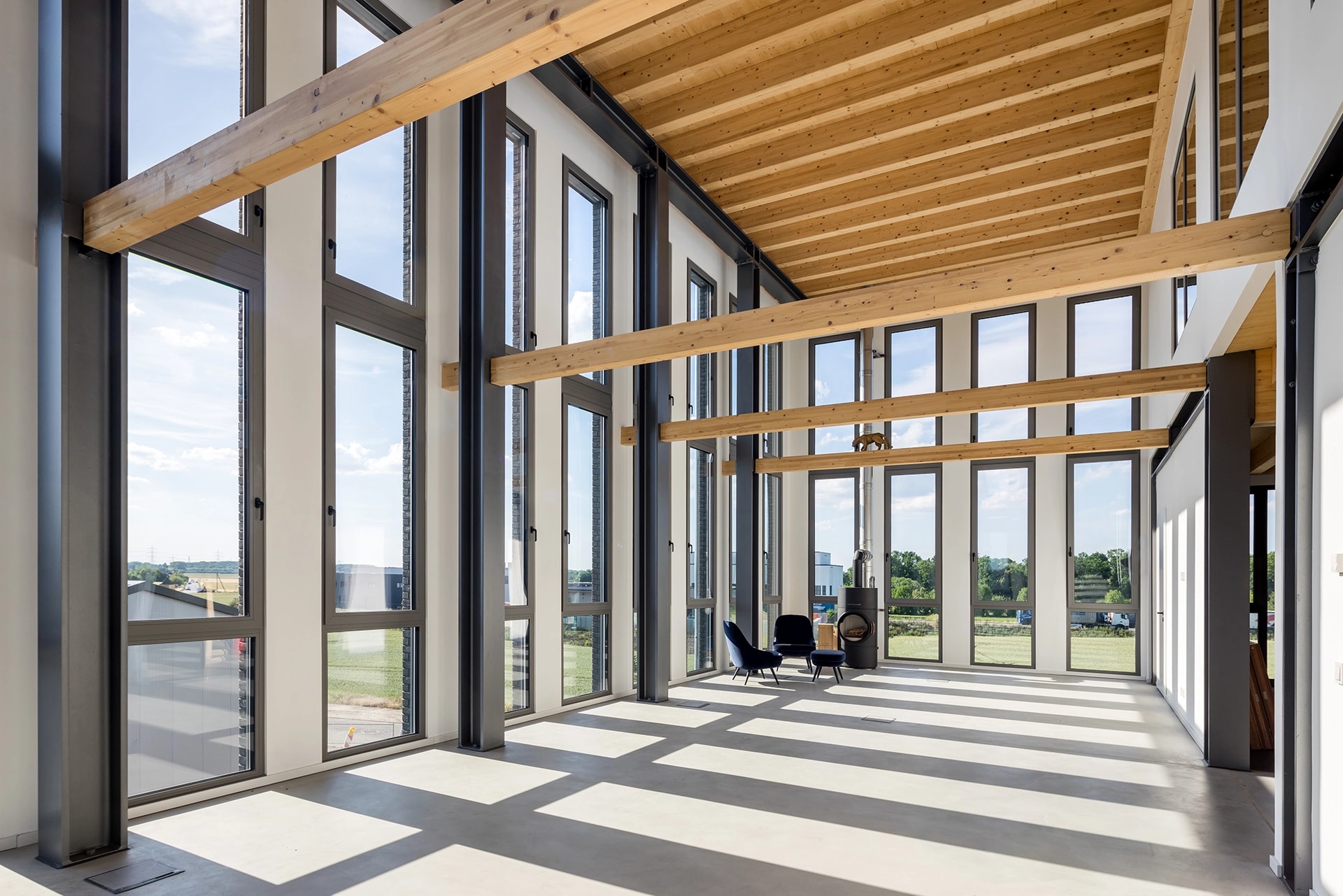 Bright interior of an X-Wood® hall with a glass façade and an exposed timber ceiling
