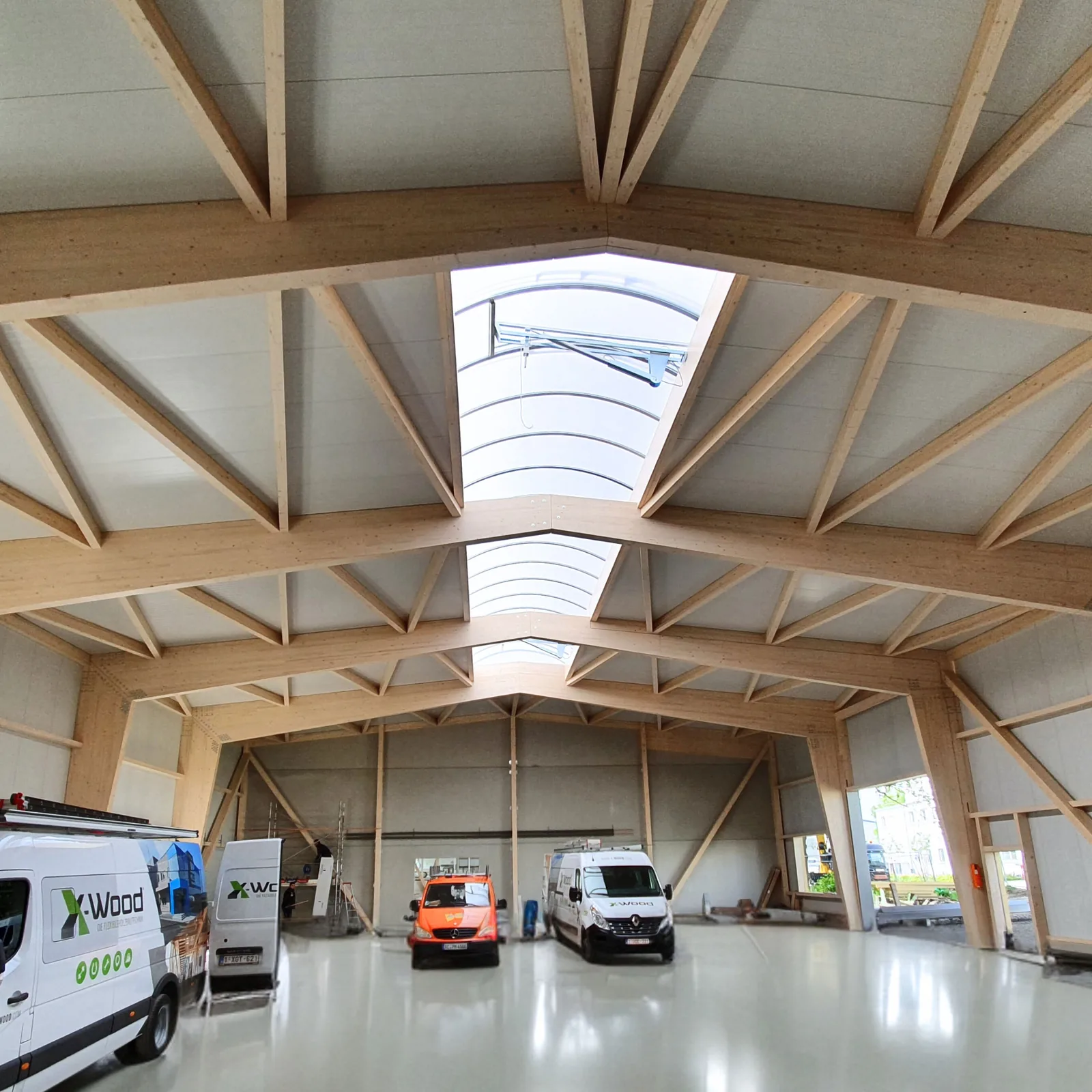 Interior of an X-Wood® timber hall with X-shaped purlins and a ridge rooflight