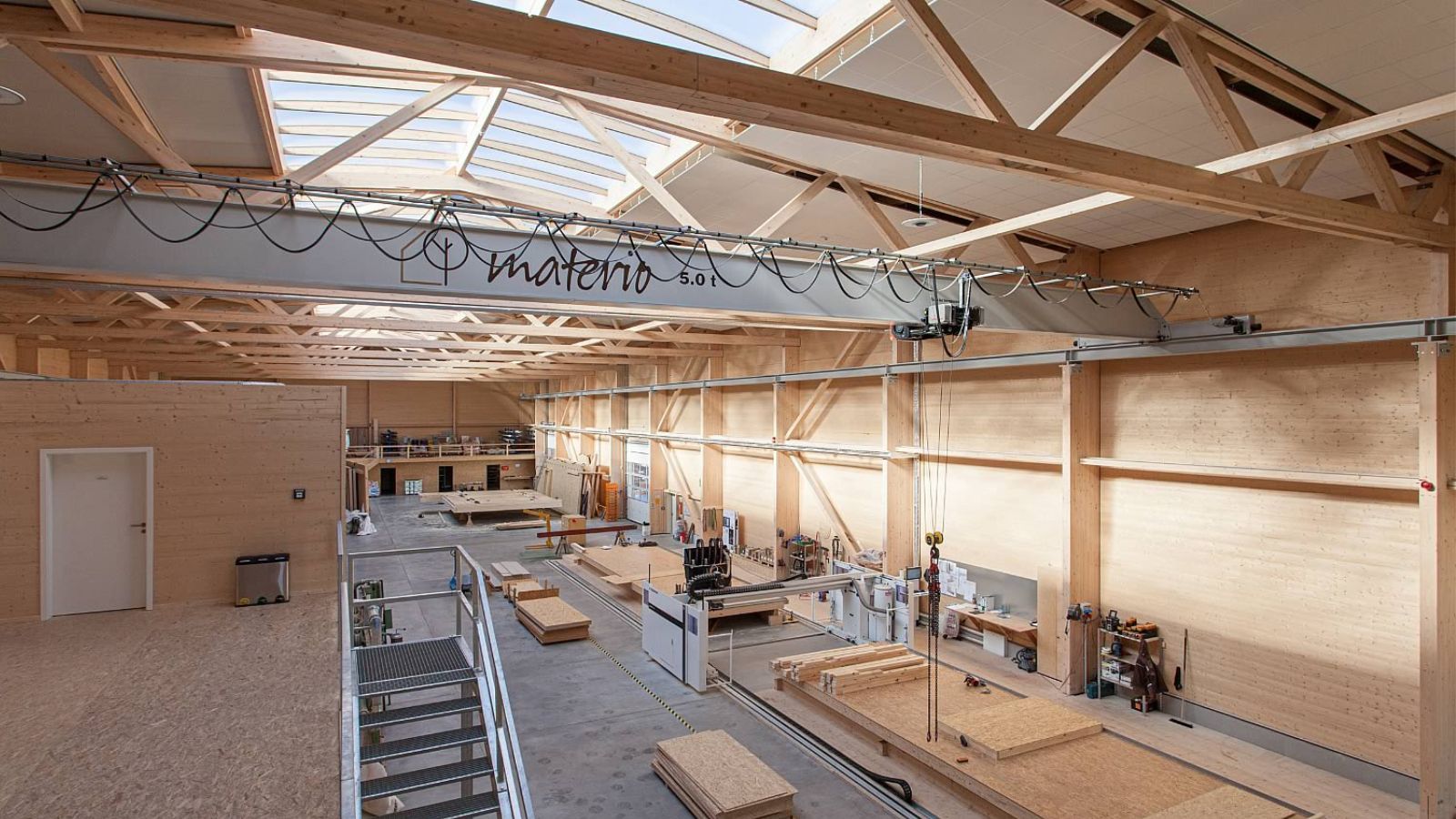 Innenansicht der Produktionshalle bei Materio in Soest mit Hallenkran inklusive „Materio“-Beschriftung und sichtbarer Holzkonstruktion von X-Wood®.