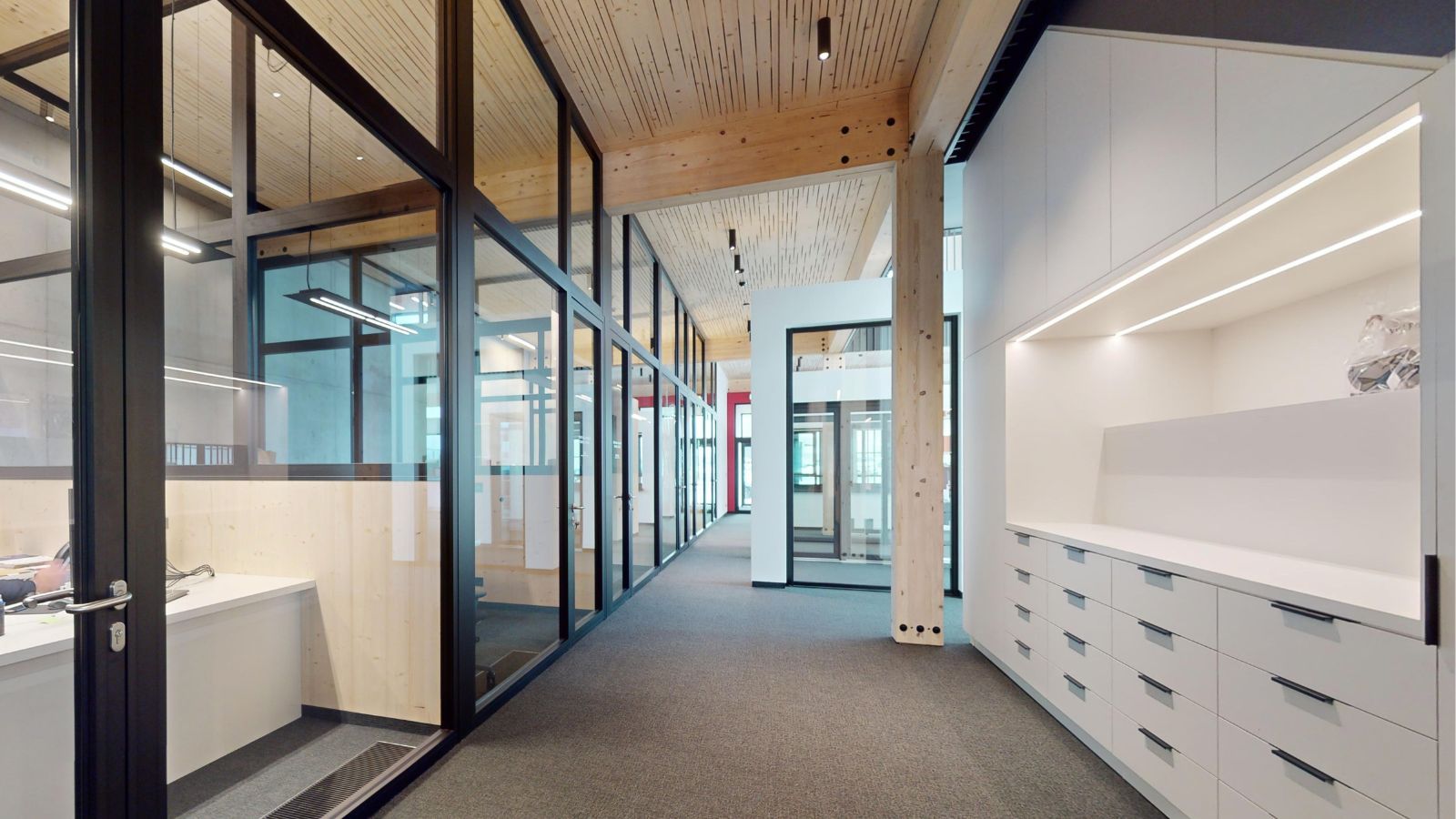 Moderner Büroflur mit Glaswänden und Holzdecken im Verwaltungsbereich von Brever