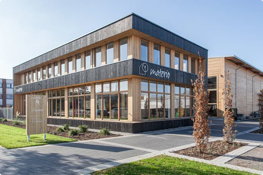 Exterior view of the two-storey materio office building in Soest, with a timber façade, ribbon windows and the company logo.